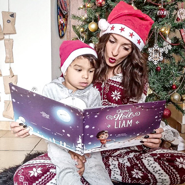 Une maman et son enfant en train de lire leur livre personnalisé de Noël. Le meilleur cadeau de Noël.